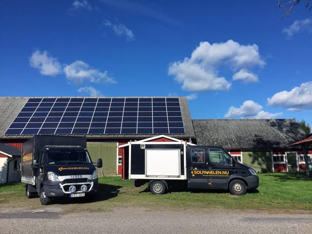 Solpanelen-bilar parkerade framför byggnad med solpaneler
