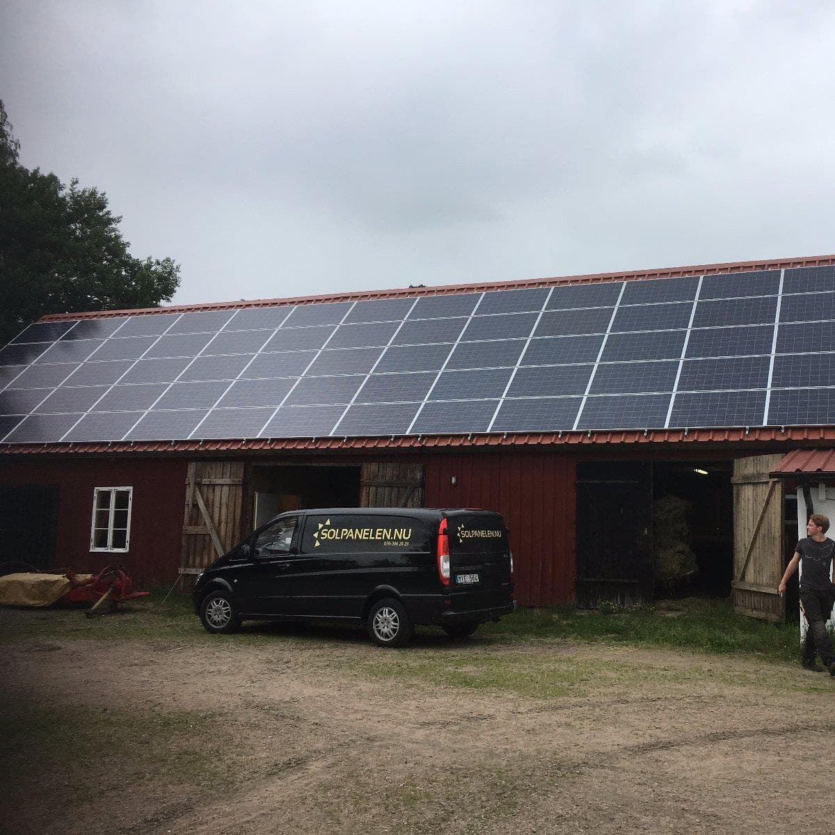 Stallbyggnaden med solpaneler på taket och en skåpbil parkerad framför
