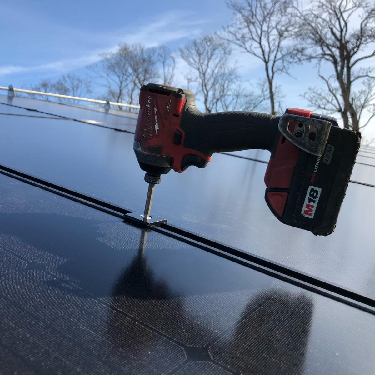 Montör som installerar solpaneler med skruvdragare på taket