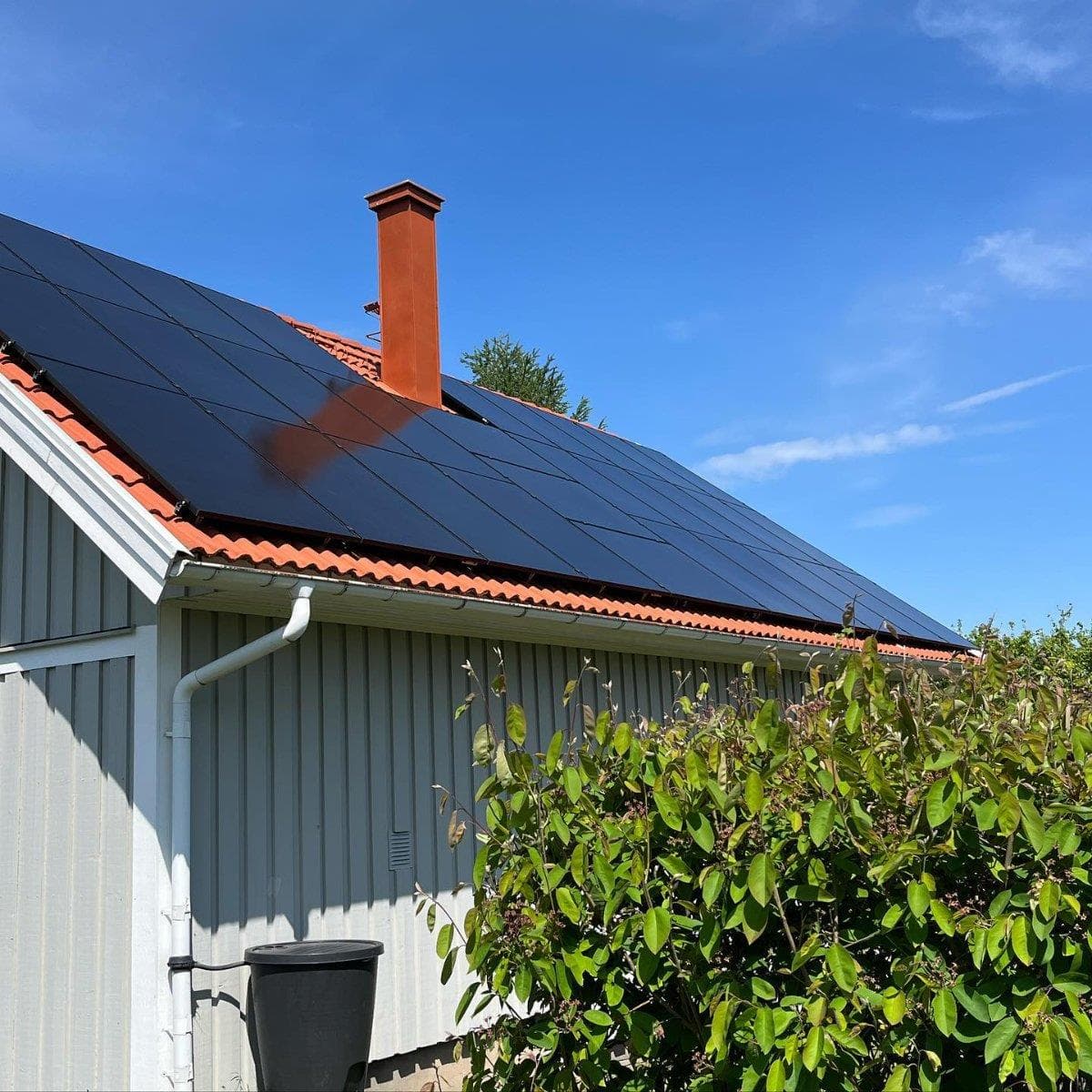 Solpaneler på ett rött tegeltak på en ljusgrå villa i Småland