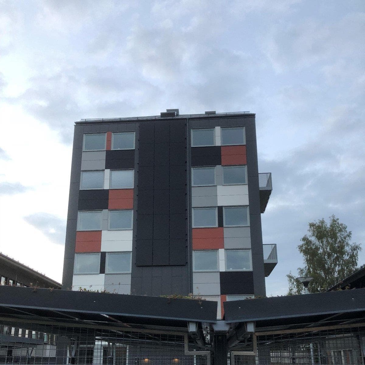 Studentboendets moderna fasad med svarta, vita och röda panelfält