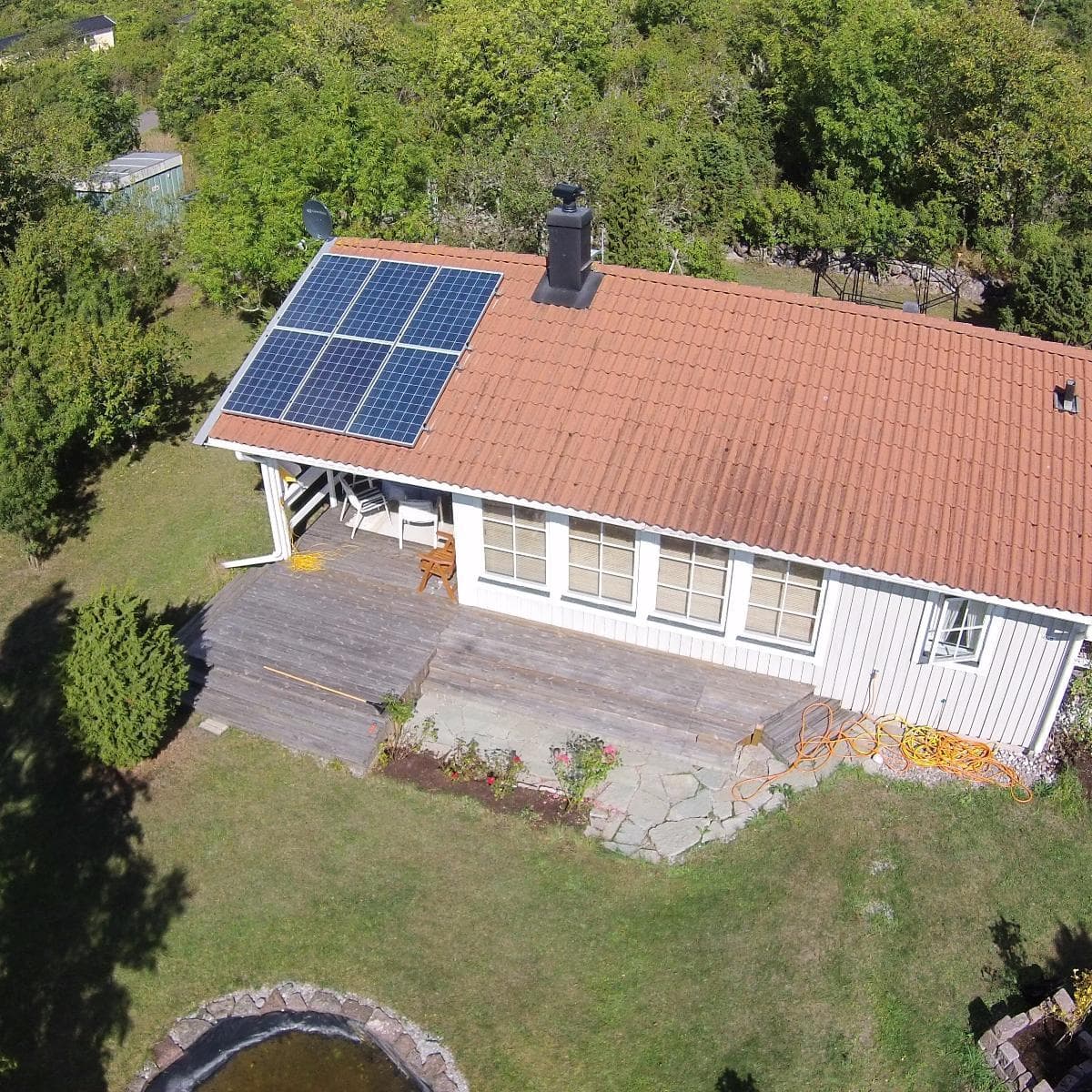 En röd borrmaskin används för att installera solpaneler under en klarblå himmel.