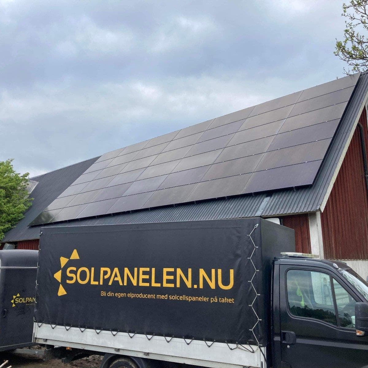 Ladugård med ett stort fält av solpaneler på taket och Solpanelens lastbil intill