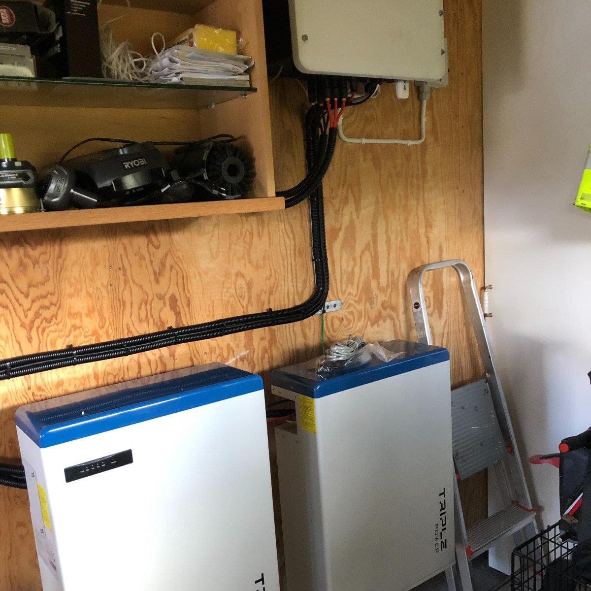 Två batterienheter från SolaX med styrenhet installerade på en trävägg