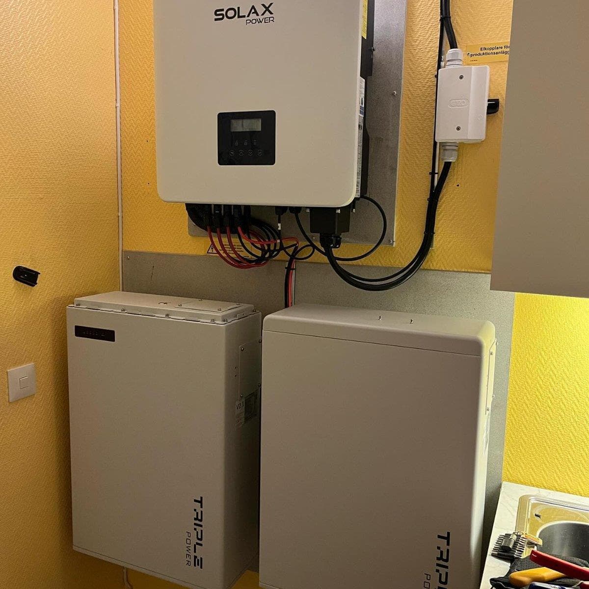 Energilagringsenheter och en SolaX Power-växelriktare monterade på en gul vägg