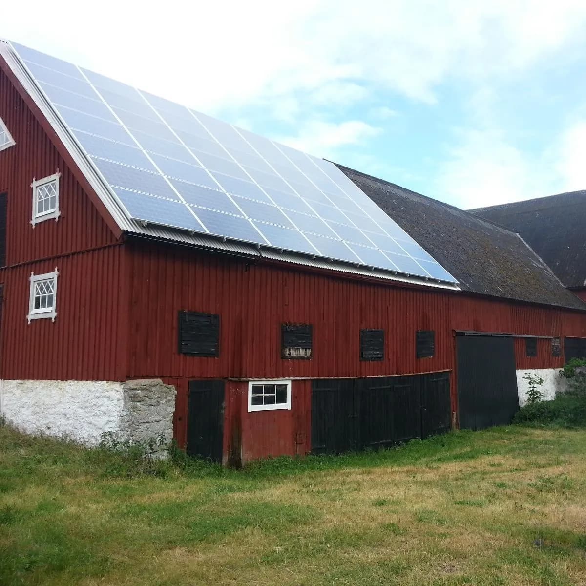 Röd ladugård med solpaneler på taket