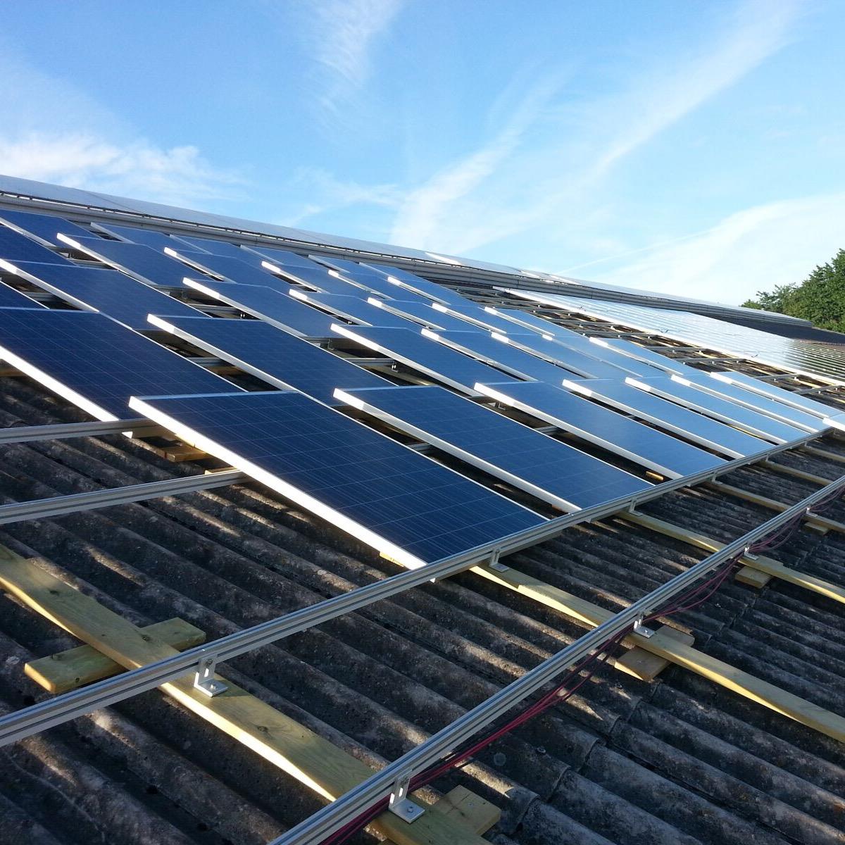 Solpaneler installerade på ett sluttande tak, under en klarblå himmel.