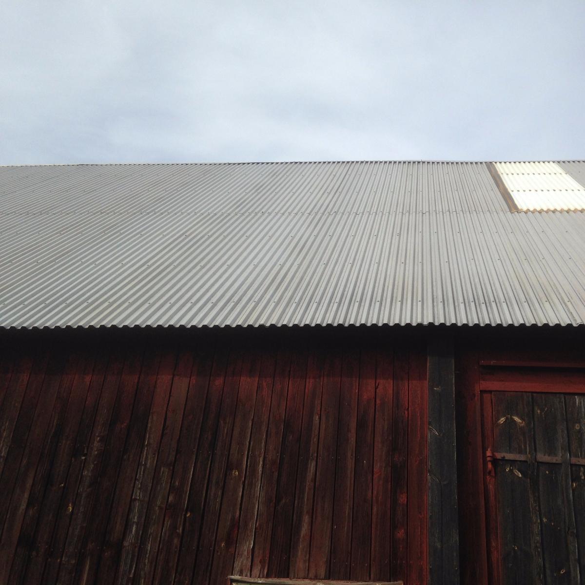 Korrugerat metalltak på en trälada under en molnig himmel.