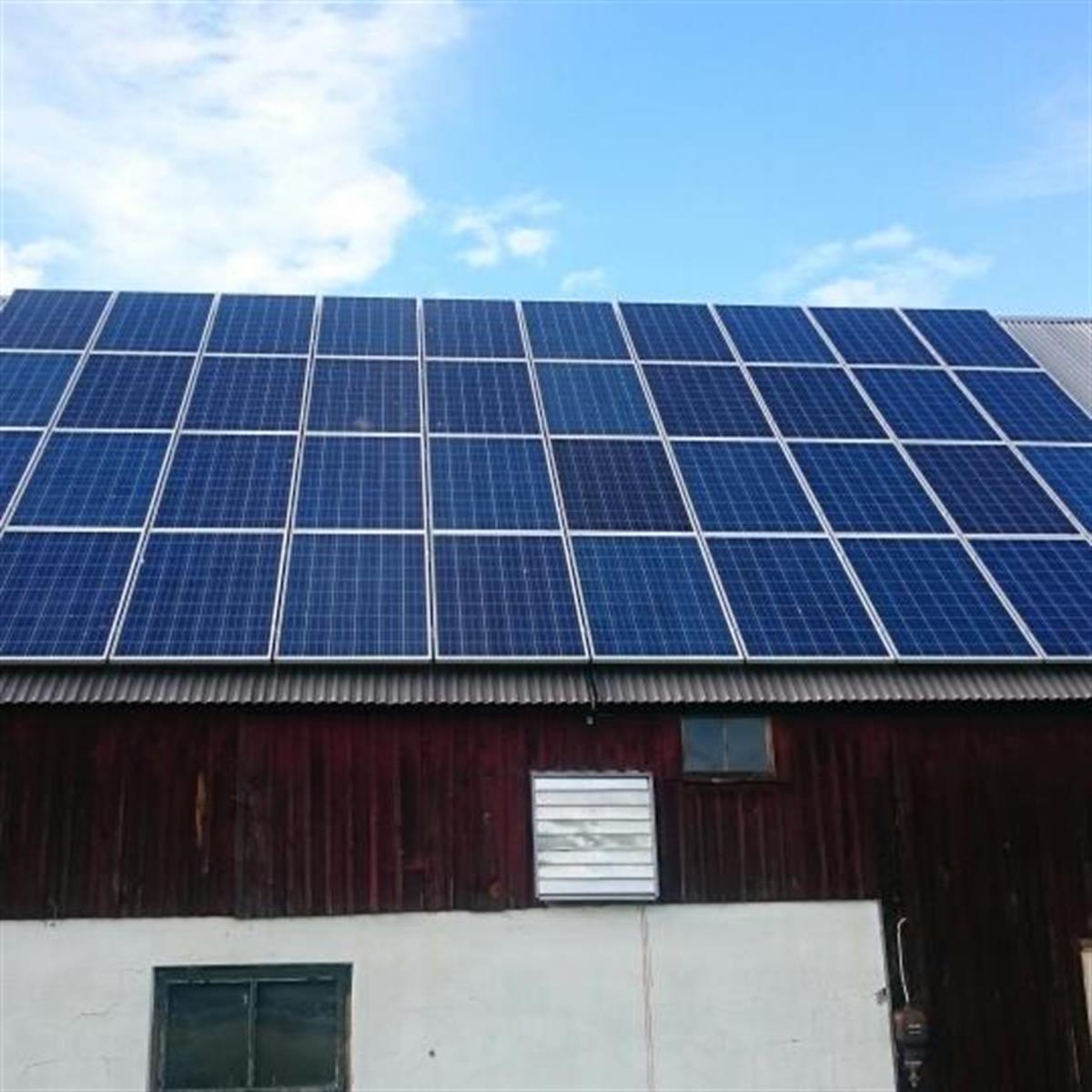 Solpaneler installerade på taket av en träkonstruktion mot en blå himmel bakgrund.