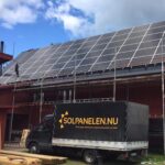 En lastbil märkt Solpanelen.nu står parkerad framför en byggnad med solpaneler som monteras på taket under delvis molnig himmel. Byggnadsställningar sätts upp runt byggnaden.