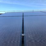 Närbild av solpaneler under en klarblå himmel, med fokus på gapet mellan två panelsektioner.